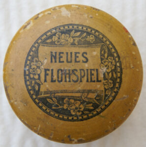 Tucker Tw ID • UNK-163c1 — AGPI ID • G-38345c1 — publisher • (unknown, German) — title • NEUES FLOHSPIEL — notes • Natural wooden mushroom-style container.